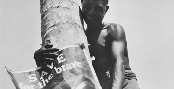 Historic image of New Guinea native beside palm tree