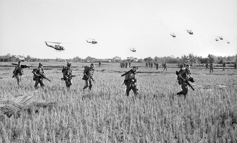 Australian air and ground military cross a paddock in Vietnam