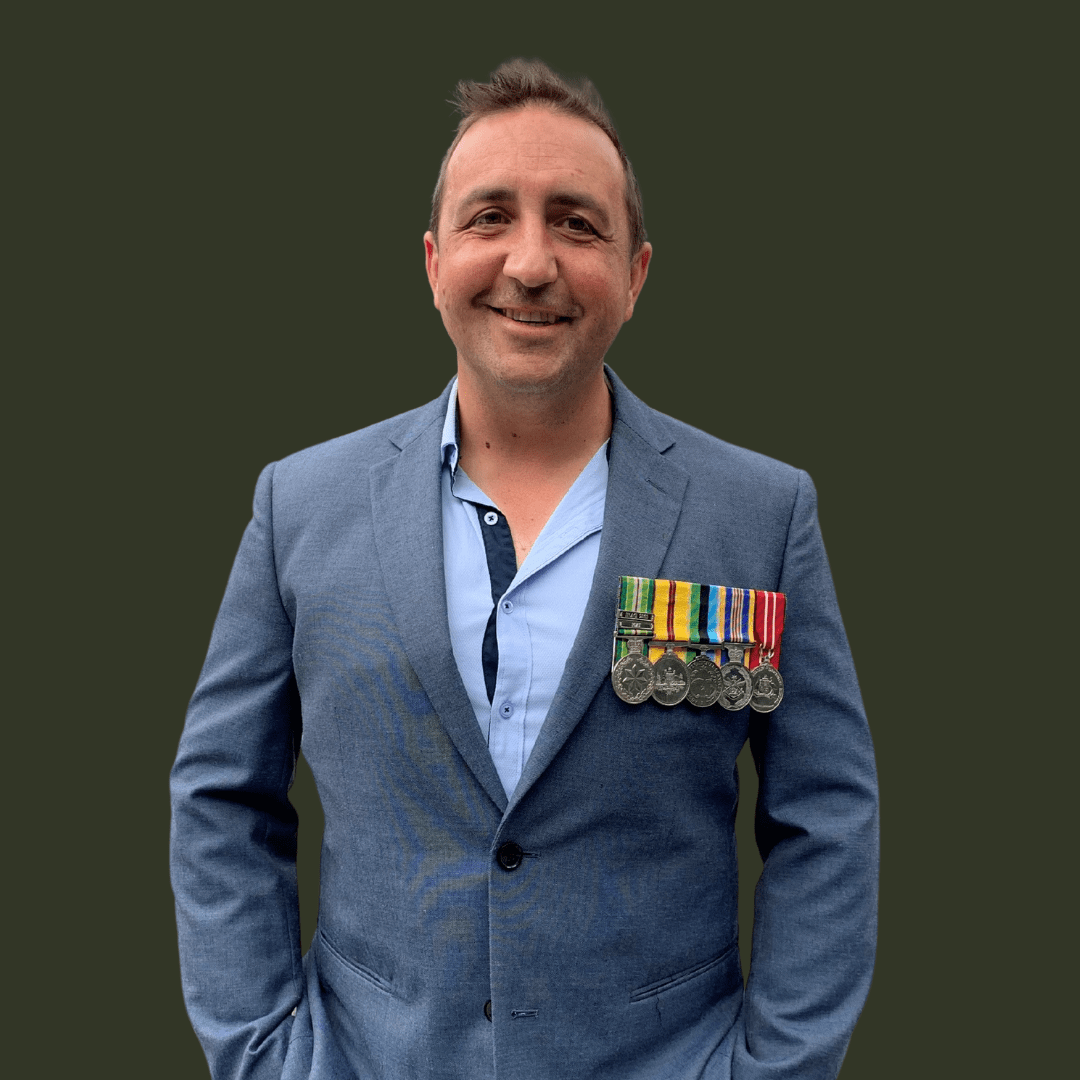 Ron Schultz, wearing a suit and smiling at the camera with his service medals. 