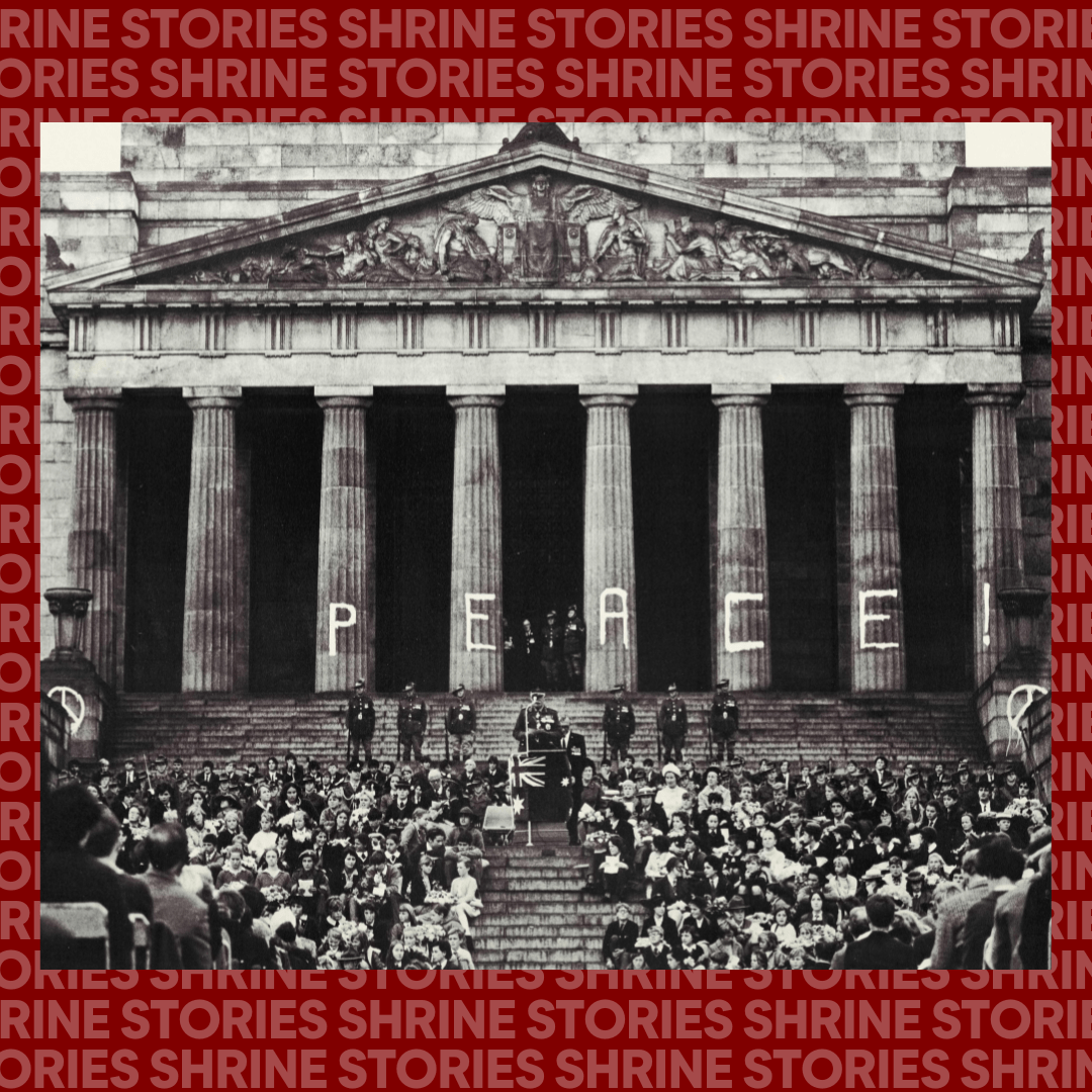 An image of the Shrine with the words 'PEACE' and two peace symbols graffitied onto the columns. The image was taking during a service, and there are six Shrine guard standing on the steps. In between them is someone speaking at a microphone. There is a large crowd gathered below. 